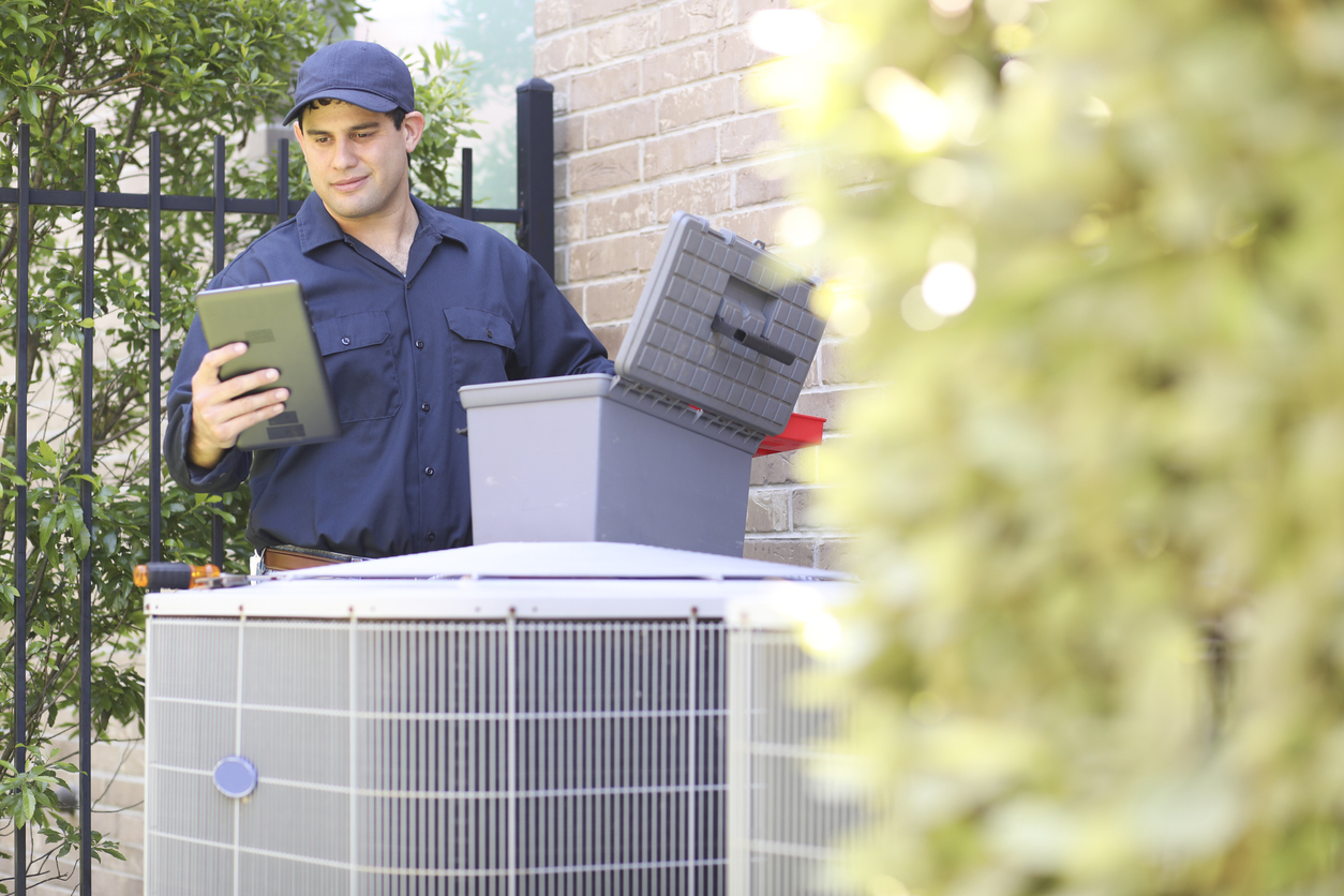 Latin descent, blue collar air conditioner repairman at work.